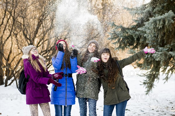 Caucasian girls throwing snow in field