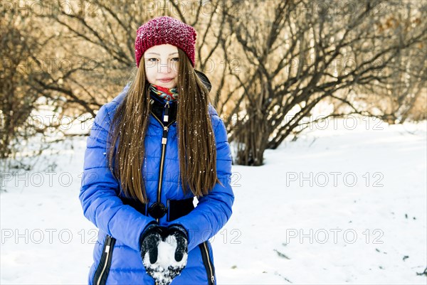 Caucasian girl holding snow in field