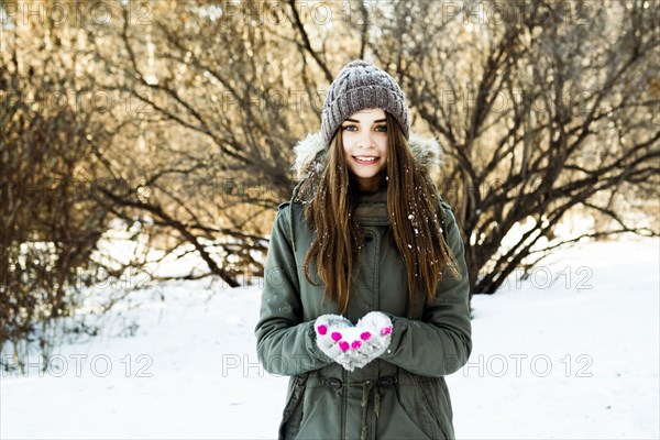 Caucasian girl holding snow in field