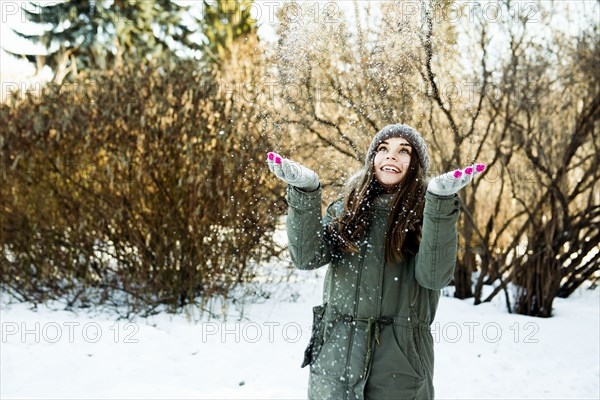 Caucasian girl throwing snow in field