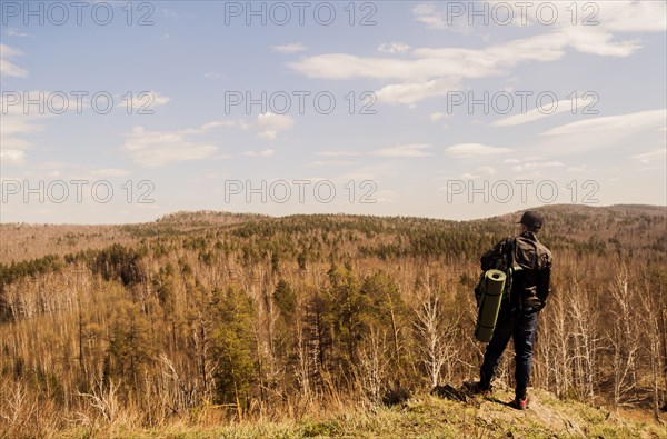 Caucasian man with camping gear overlooking rural forest