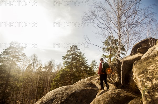 Caucasian man hiking on rock formations in remote forest