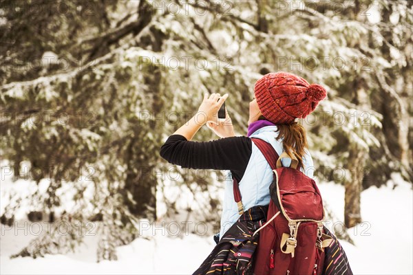 Caucasian woman photographing nature on snowy path