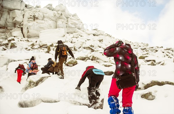 Caucasian hikers climbing snowy rock formations