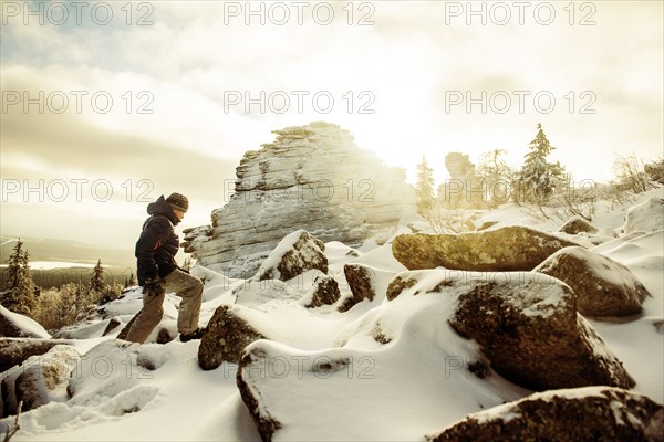 Caucasian hiker climbing snowy rock formations