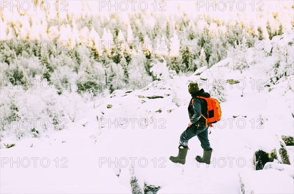 Caucasian hiker climbing snowy rock formations