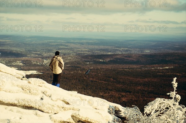 Caucasian hiker admiring scenic view on snowy mountaintop