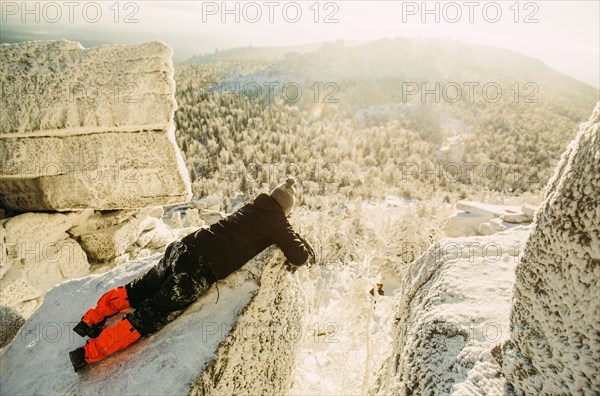 Caucasian hiker laying on snowy rock formations