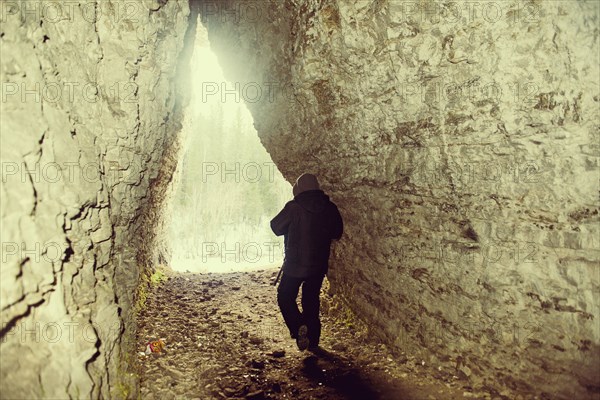 Caucasian hiker walking in rocky cave