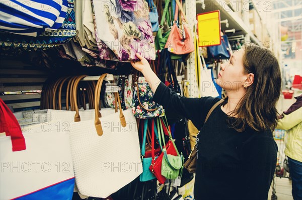 Caucasian woman shopping for purse in store