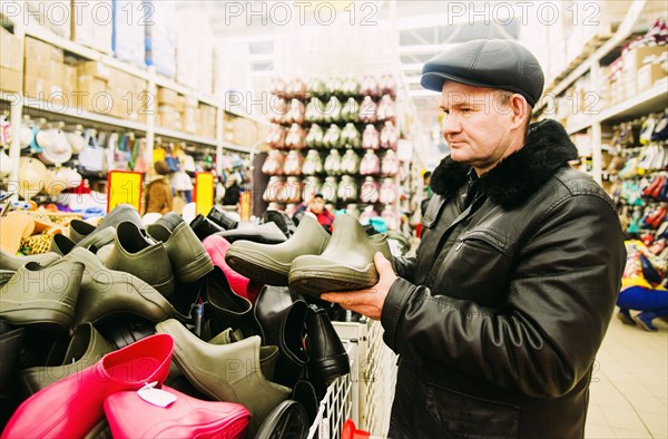 Caucasian man shopping for rain boots in store