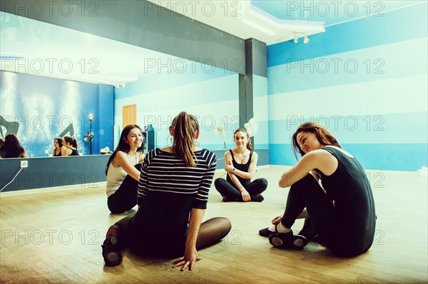 Caucasian dancers sitting on studio floor
