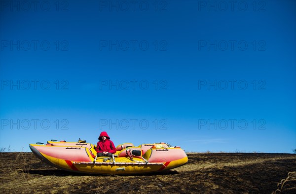 Caucasian boy sitting on catamaran in rural field