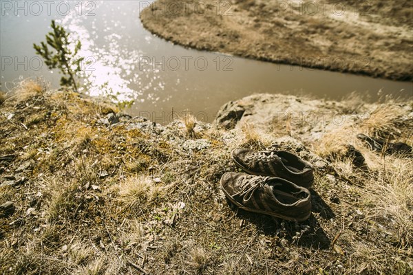 Close up of abandoned shoes over remote river