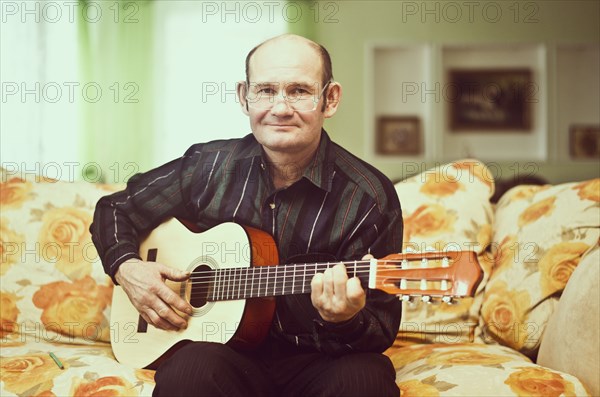 Caucasian man playing guitar on sofa