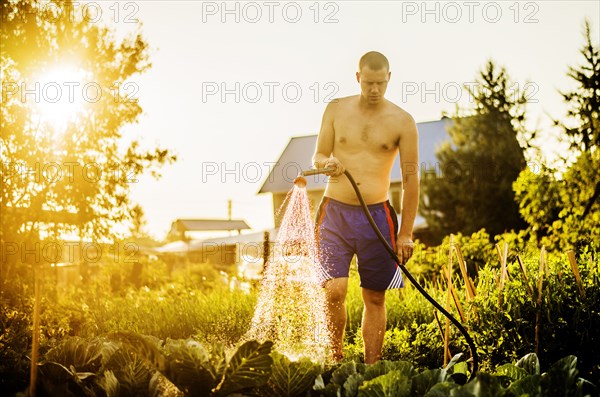 Caucasian man watering plants in backyard