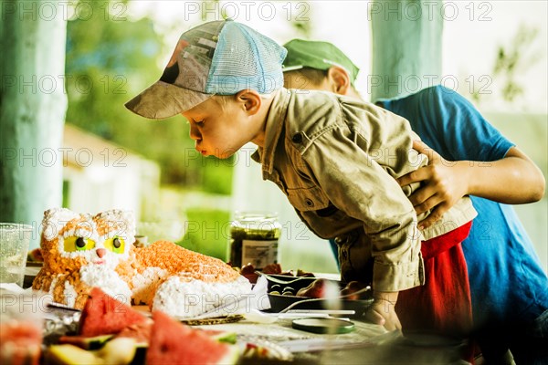 Caucasian boy blowing out candles on birthday cake