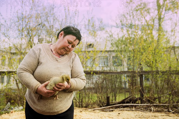 Caucasian farmer holding duckling on farm