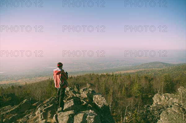 Caucasian hiker admiring view from remote rock formation