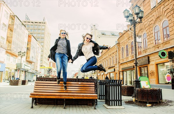 Women jumping for joy near bench