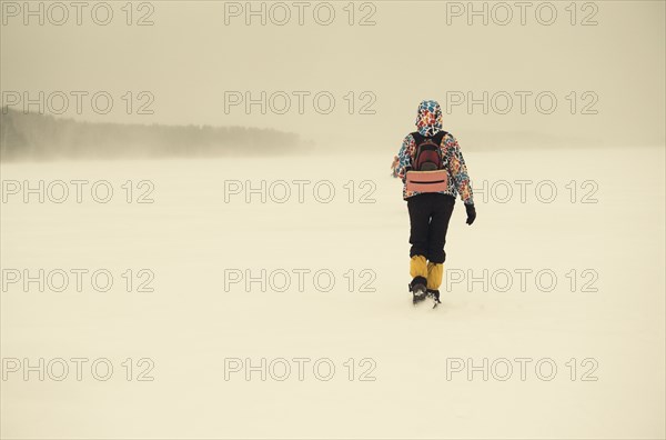 Caucasian hiker walking in snowy remote field