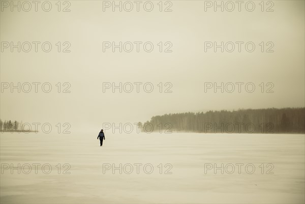 Caucasian hiker walking in snowy remote field