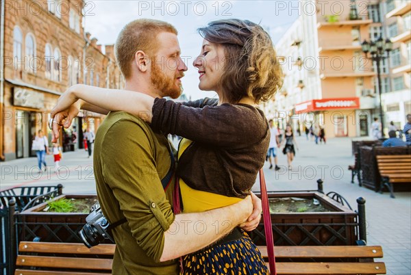 Caucasian couple hugging in city