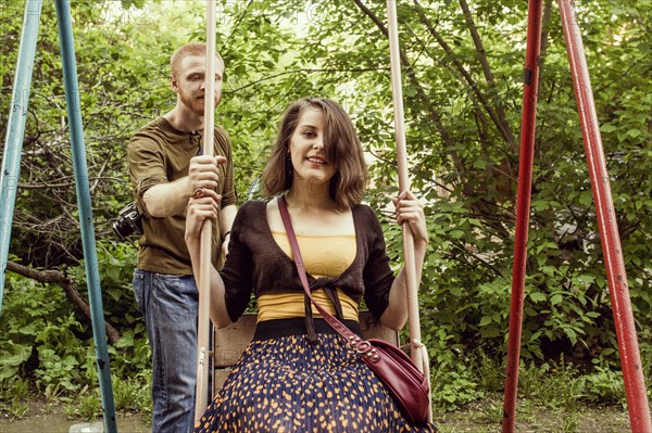 Caucasian couple playing on swing set