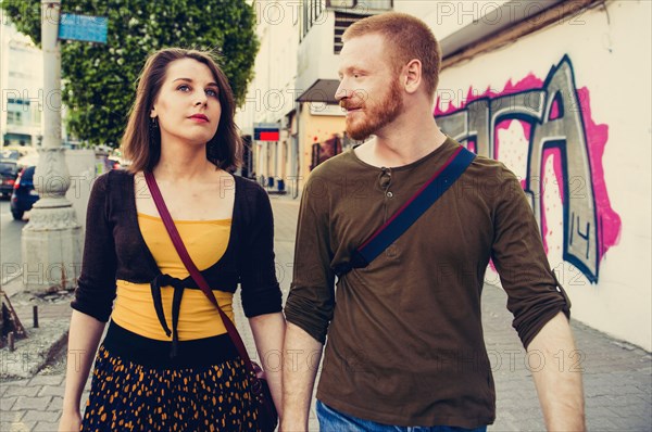 Caucasian couple walking on city sidewalk