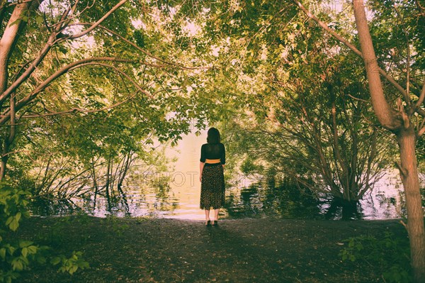 Caucasian woman standing under trees near river