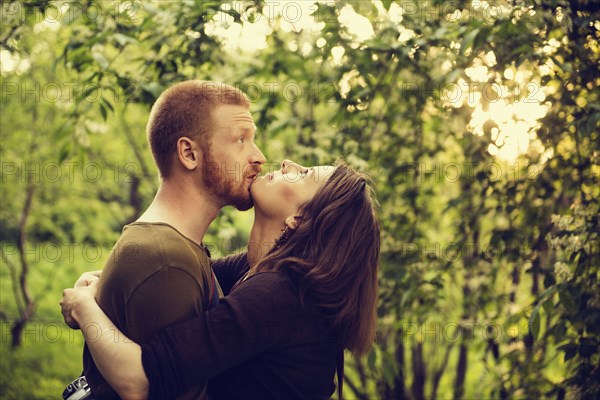 Caucasian couple hugging near trees