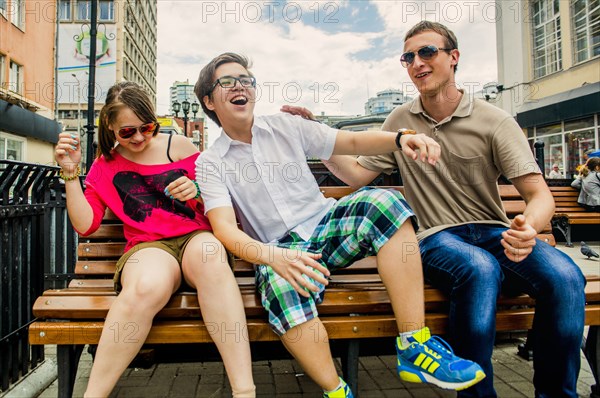 Caucasian friends playing on city bench