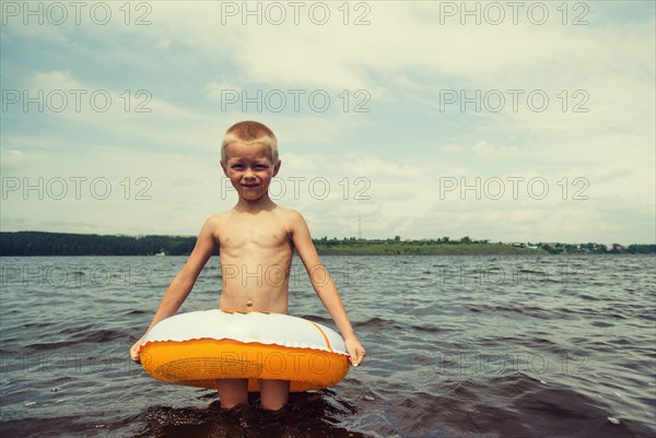Caucasian boy playing in inner tube in lake