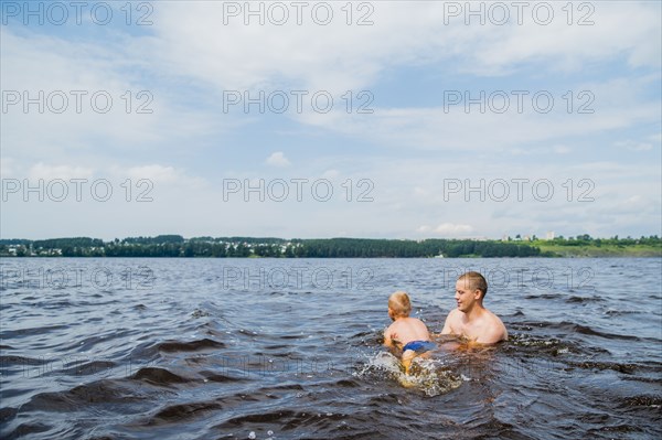 Caucasian father and son swimming in lake