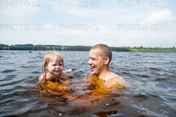 Caucasian father and daughter swimming in lake