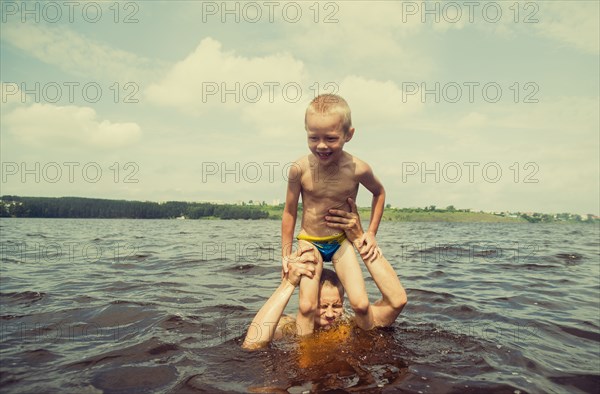 Caucasian father and son swimming in lake