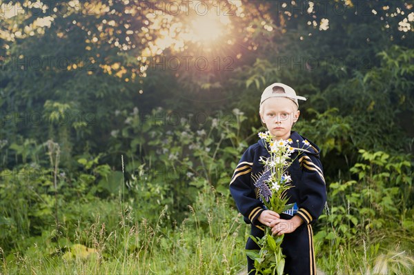 Caucasian boy picking flowers in rural field