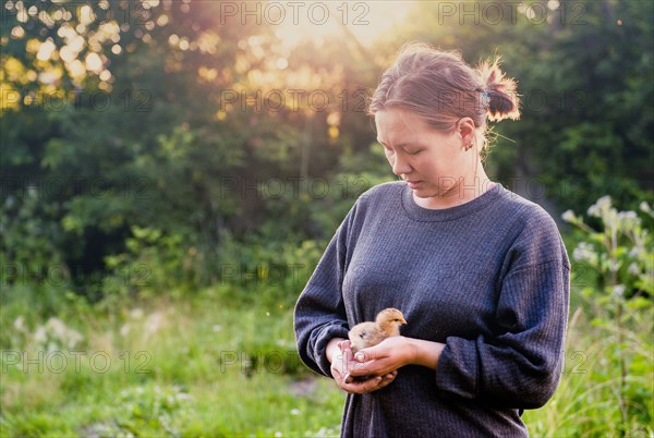Caucasian woman holding chick in garden