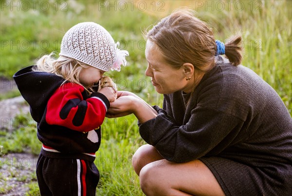 Caucasian mother and daughter playing with chick in garden