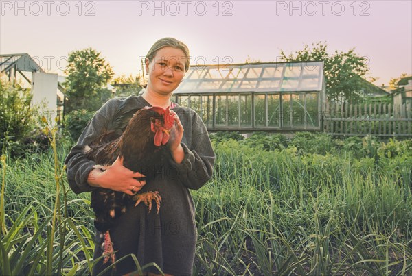 Caucasian farmer holding chicken in garden