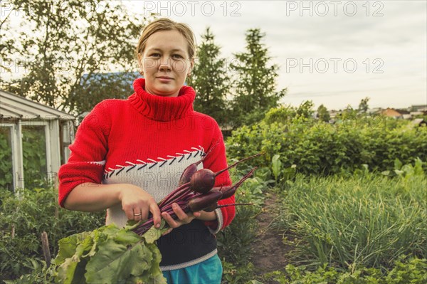 Caucasian farmer holding fresh beets in garden