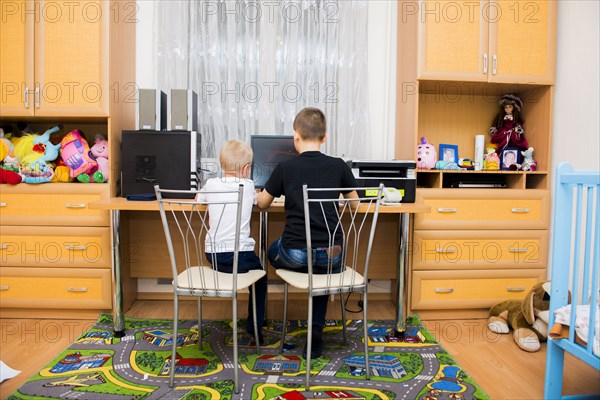 Caucasian brothers using computer in bedroom