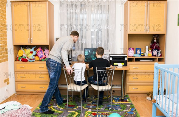 Caucasian father and sons using computer in bedroom