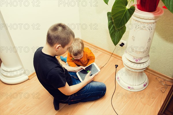 Caucasian brothers using digital tablet on floor