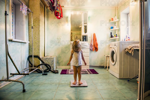 Caucasian girl standing on scale in bathroom