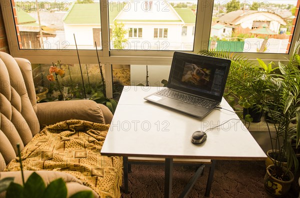 Laptop and mouse by armchair at desk