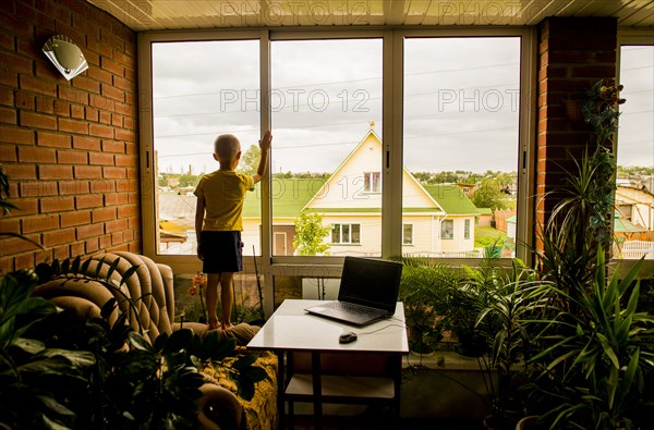 Caucasian boy looking out living room window