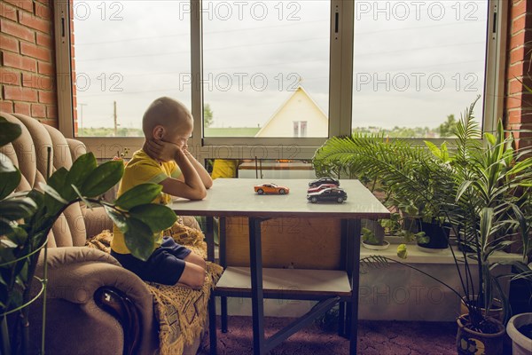 Caucasian boy playing with toy cars at desk