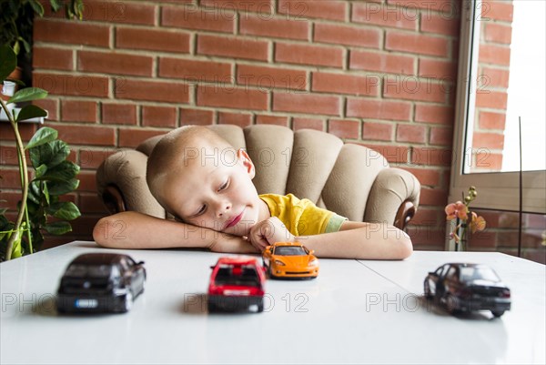 Caucasian boy playing with toy cars at desk