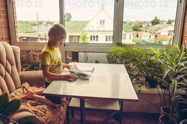 Caucasian boy reading magazine at desk